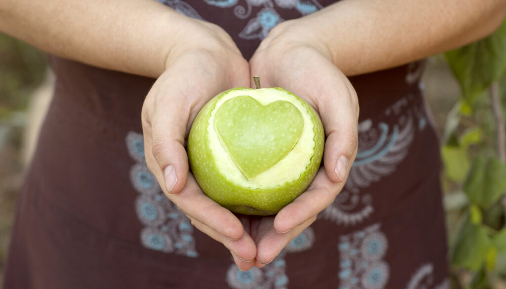 Hands,Holding,An,Apple,With,Heart,Shape,Cut,Out