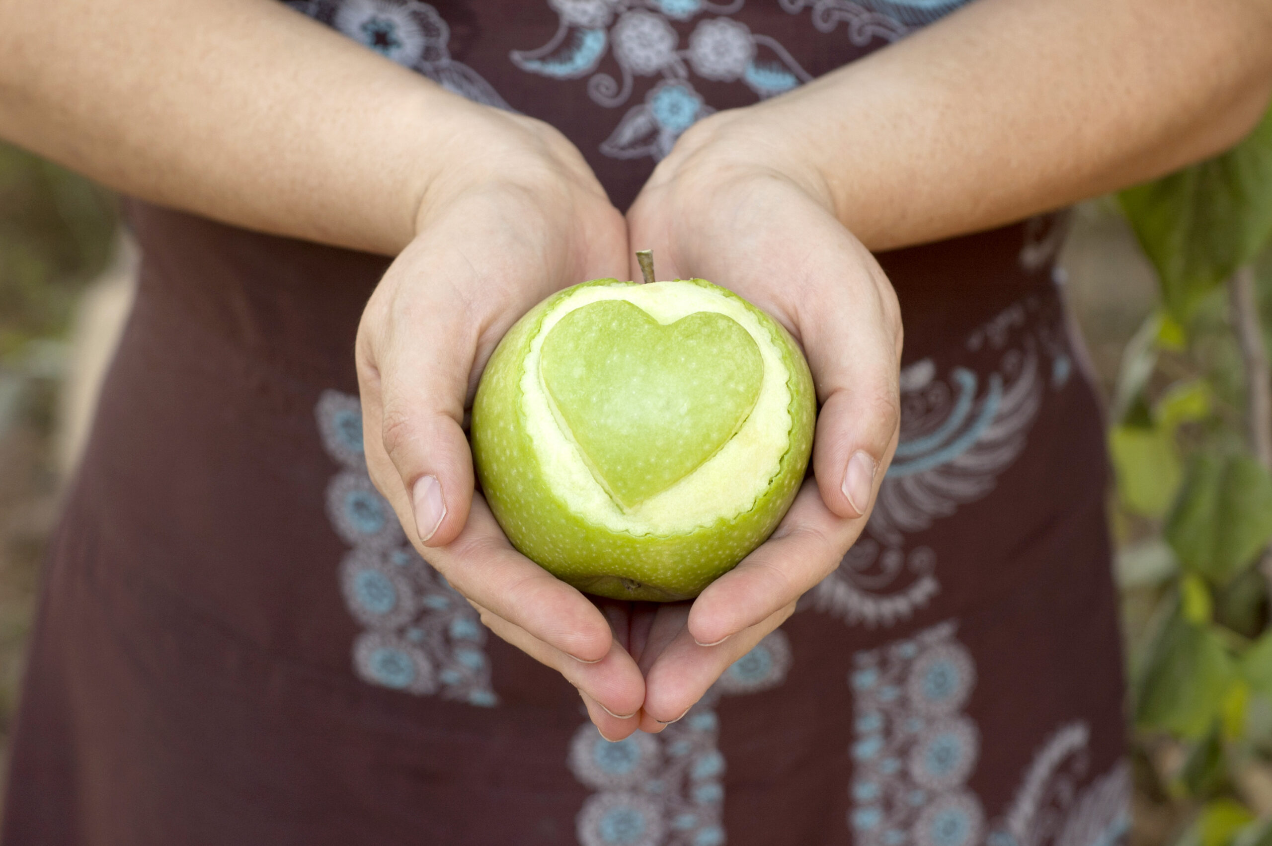 Hands,Holding,An,Apple,With,Heart,Shape,Cut,Out